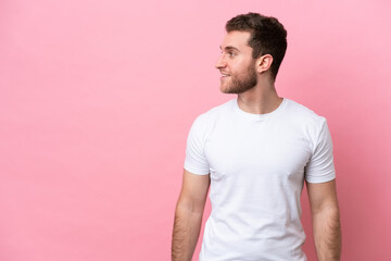 Obraz premium Young caucasian man isolated on pink background looking side