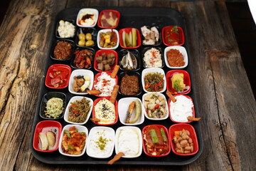 Turkish and Greek appetizers (meze) table. Traditional Turkish cuisine cold appetizers. Different types of appetizers in colorful special plates. Olives, hummus, yoghurt, pickles etc. Selective focus.
