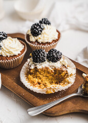 muffin cupcake paper mold carrot cake topped with whipped cream and berries 
blackberry