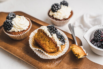 muffin cupcake paper mold carrot cake topped with whipped cream and berries 
blackberry