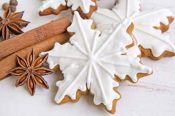 Christmas gingerbread. Edible Christmas decor concept. Gingerbread cookies in white glaze, cinnamon and spices on a light wooden background. Christmas traditions. Copy space. Flat layout. - 521880591