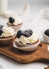 muffin cupcake paper mold carrot cake topped with whipped cream and berries 
blackberry