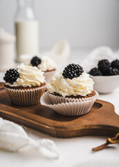 muffin cupcake paper mold carrot cake topped with whipped cream and berries 
blackberry