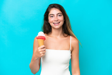 Young woman in swimsuit holding an ice cream isolated on blue background smiling a lot