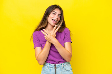 Young caucasian woman isolated on yellow background smiling and showing victory sign