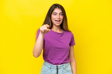 Young caucasian woman isolated on yellow background surprised and pointing front