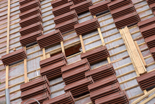 Roof building at new house construction. Brown roof tiles covering estate