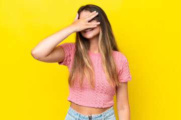 Young caucasian woman isolated on yellow background covering eyes by hands and smiling