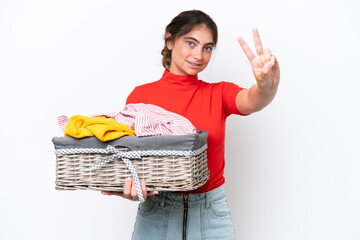 Young caucasian woman holding a clothes basket isolated on white background smiling and showing...