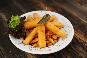 Potato croquettes with french fries on the white plate. Delicious unhealthy appetizer. Beer platter on wooden background with pickles. Snack for beer or drink.