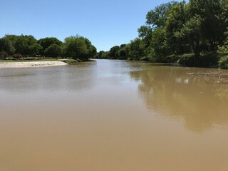 Closeup of the Trinity River surrounded by trees reflecting in the water surface near Rosser, Texas