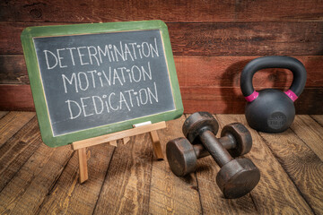 determination, motivation and dedication - inspirational text in white chalk on a slate blackboard...