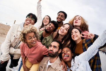 Big group of cheerful young friends taking selfie portrait fool around. Happy people having fun. Concept of community, youth lifestyle and friendship