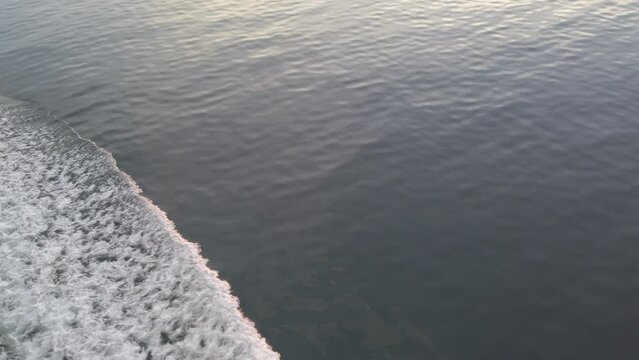 4k POV footage panning from bow wave to serene ocean sunset scene