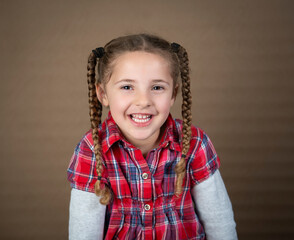 Smiling cute toddler with brown braids in red plaid cowgirl shirt - 521885313