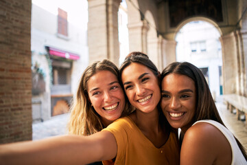 Fototapeta premium three happy female friends having fun together and taking smiling selfie