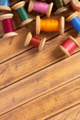 Sewing thread spool at wooden background. Wood bobbin with thread on tabletop