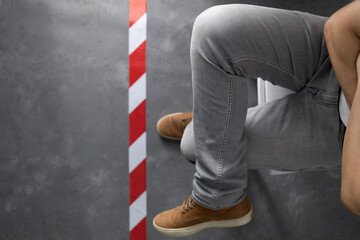 Man sitting on chair near signal warning tape at cement floor background. Moving forward concept idea