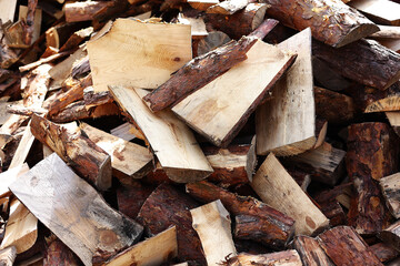 close up of pile of chopped firewood tree logs at lumber mill. Preparation for winter time. natural wood texture background. Fireplace or stove material. Timber industry concept.