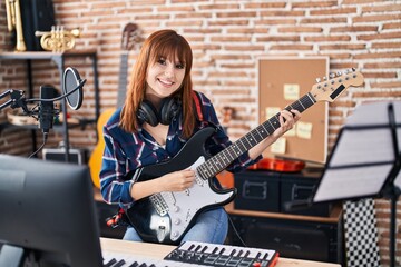 Fototapeta na wymiar Young woman musician singing song playing electric guitar at music studio