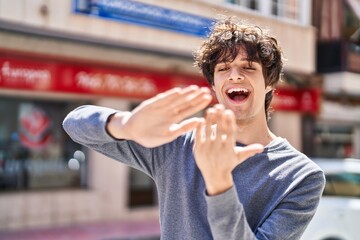 Young hispanic man smiling confident doing spend money gesture at street