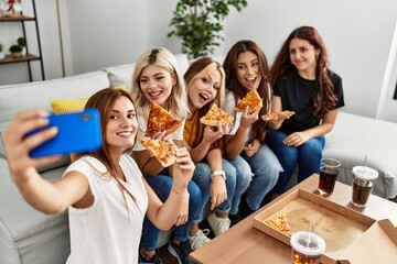 Group of young woman friends make selfie by the smartphone eating pizza at home.