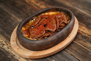 Delicious Fried eggs with pastrami inside in a casserole on wooden background. Fried eggs with pastrami made with butter.