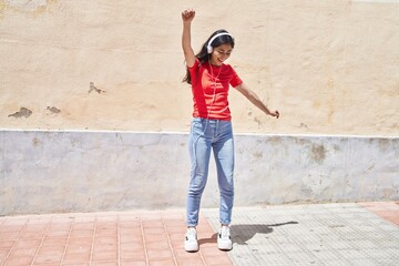 Obraz na płótnie Canvas Young hispanic girl smiling confident listening to music at street