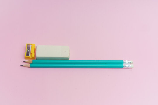 L&aacute;pices azules, borrador blanco y sacapuntas amarillo sobre fondo rosa.