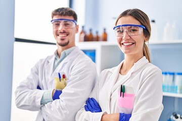 Young man and woman scientists workers standing with arms crossed gesture at laboratory