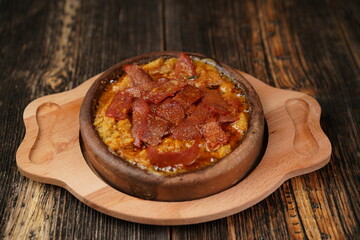 Delicious Fried eggs with pastrami inside in a casserole on wooden background. Fried eggs with pastrami made with butter. 