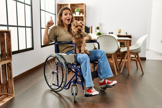 Young hispanic girl sitting on wheelchair at home looking stressed and nervous with hands on mouth biting nails. anxiety problem.