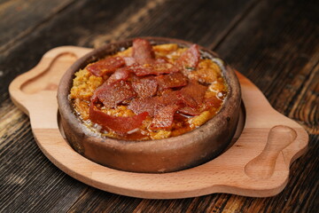 Delicious Fried eggs with pastrami inside in a casserole on wooden background. Fried eggs with pastrami made with butter. 