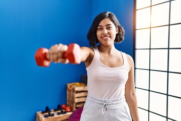 Fototapeta na wymiar Young latin woman smiling confident training using dumbbell at sport center
