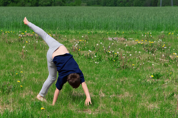 Boy makes an acrobatic wheel. On the grass. close up