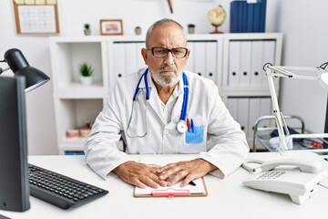 Mature doctor man at the clinic skeptic and nervous, frowning upset because of problem. negative person.