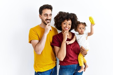 Interracial young family of black mother and hispanic father with daughter with hand on chin thinking about question, pensive expression. smiling and thoughtful face. doubt concept.