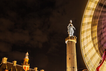 Fototapeta na wymiar ferris wheel at night with statue in europe