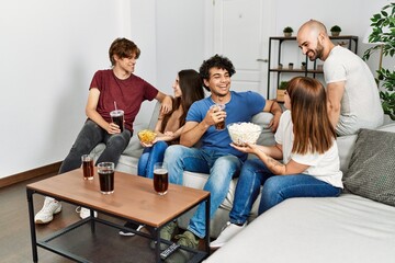 Group of young friends having party sitting on the sofa at home.