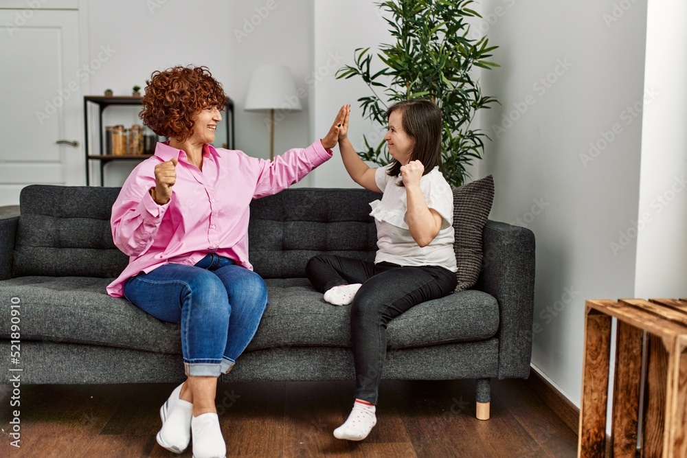 Wall mural Mature mother and down syndrome daughter at home doing high five gesture