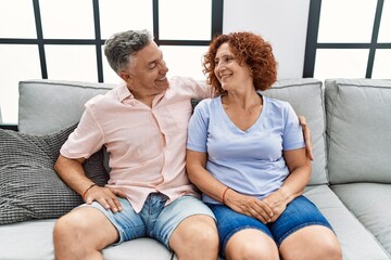 Obraz premium Middle age man and woman couple smiling confident hugging each other sitting on sofa at home