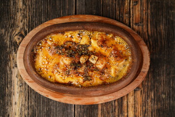 Potato gratin in the casserole on wooden background. Potato gratin made with baked potatoes, cream, cheese and rosemary. Delicious appetizer. 