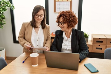 Group of two women working at the office. Mature woman and down syndrome girl working at inclusive...