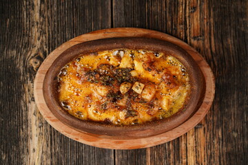 Potato gratin in the casserole on wooden background. Potato gratin made with baked potatoes, cream, cheese and rosemary. Delicious appetizer. 