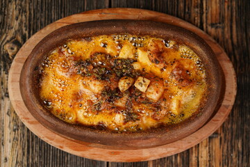 Potato gratin in the casserole on wooden background. Potato gratin made with baked potatoes, cream, cheese and rosemary. Delicious appetizer. 