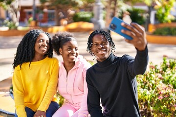 African american friends making selfie by the smartphone sitting on bench at park