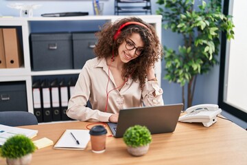 Young hispanic woman business worker listening to music working at office