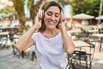 Young hispanic woman smiling confident listening to music at park