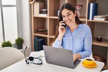 Young woman talking on the smartphone working at home