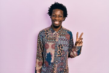 Young african american man wearing casual clothes smiling with happy face winking at the camera doing victory sign. number two.